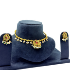 Gold necklace and earrings set on a blue velvet stand with a white background