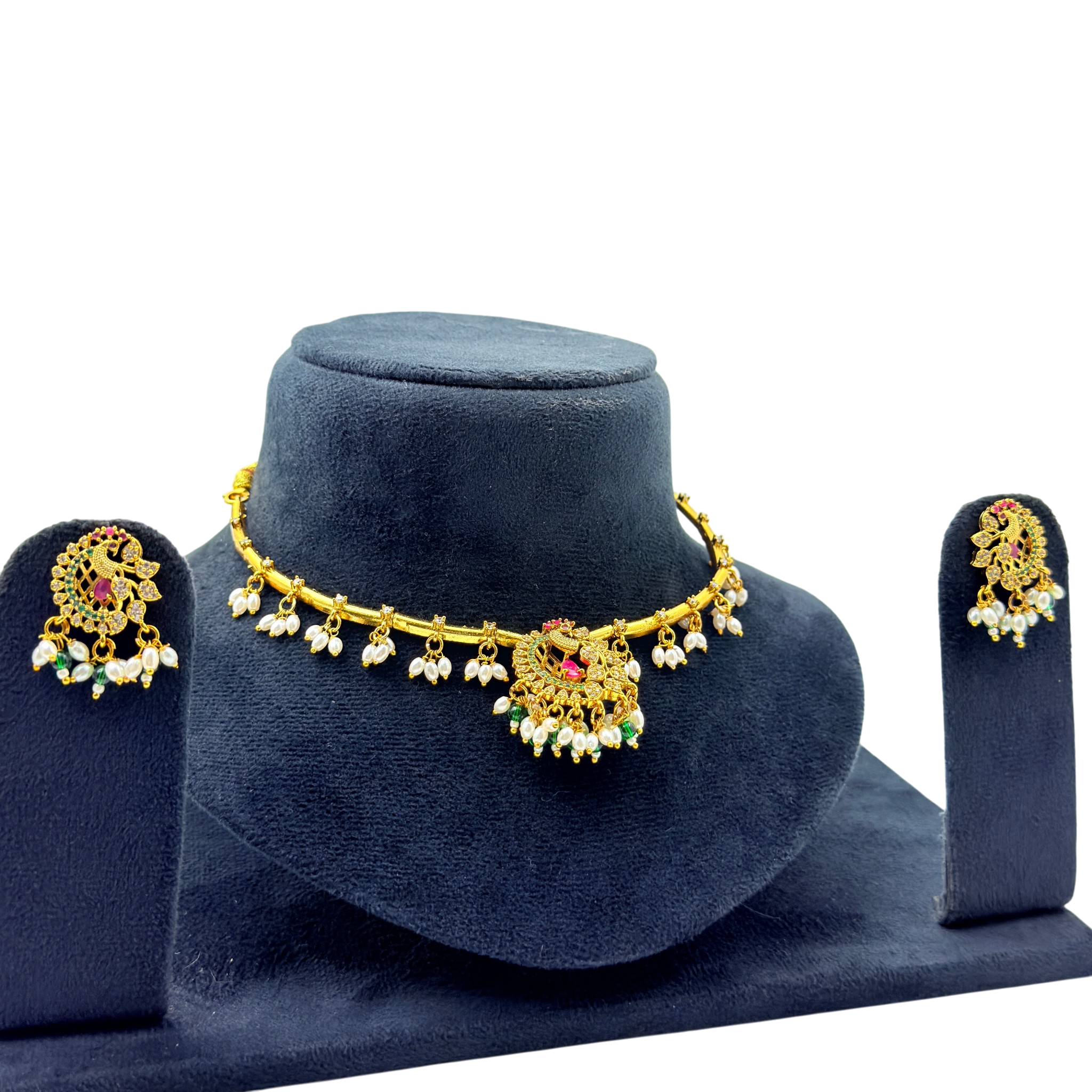 Gold necklace and earrings set on a blue velvet stand with a white background