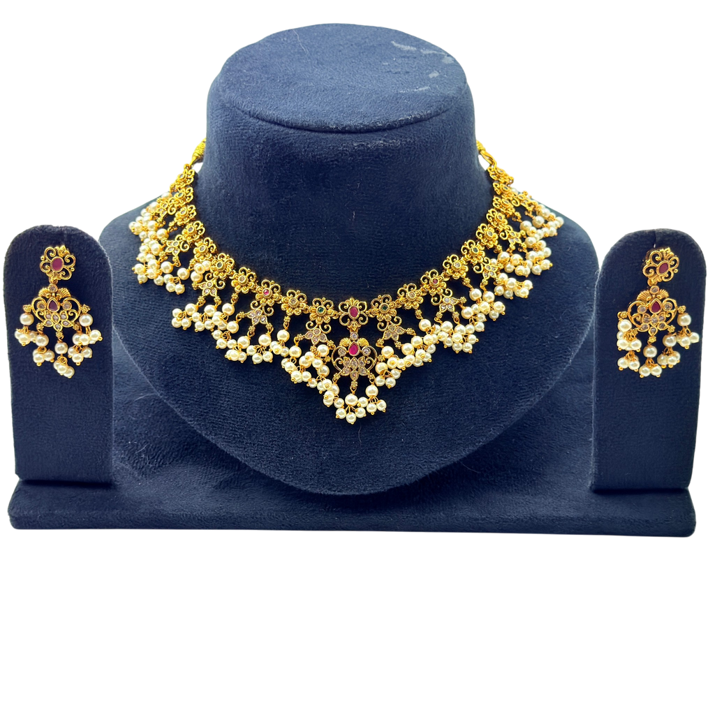 Gold necklace and earrings set on a blue stand with a white background