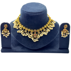 Gold necklace and earrings set on a blue stand with a white background