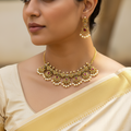 Woman wearing a gold necklace and earrings with a blurred background