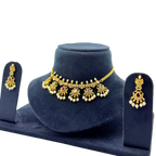 Gold necklace and earrings set on a blue velvet stand with a white background