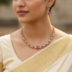 Woman wearing a gold necklace with pink gemstones and matching earrings.