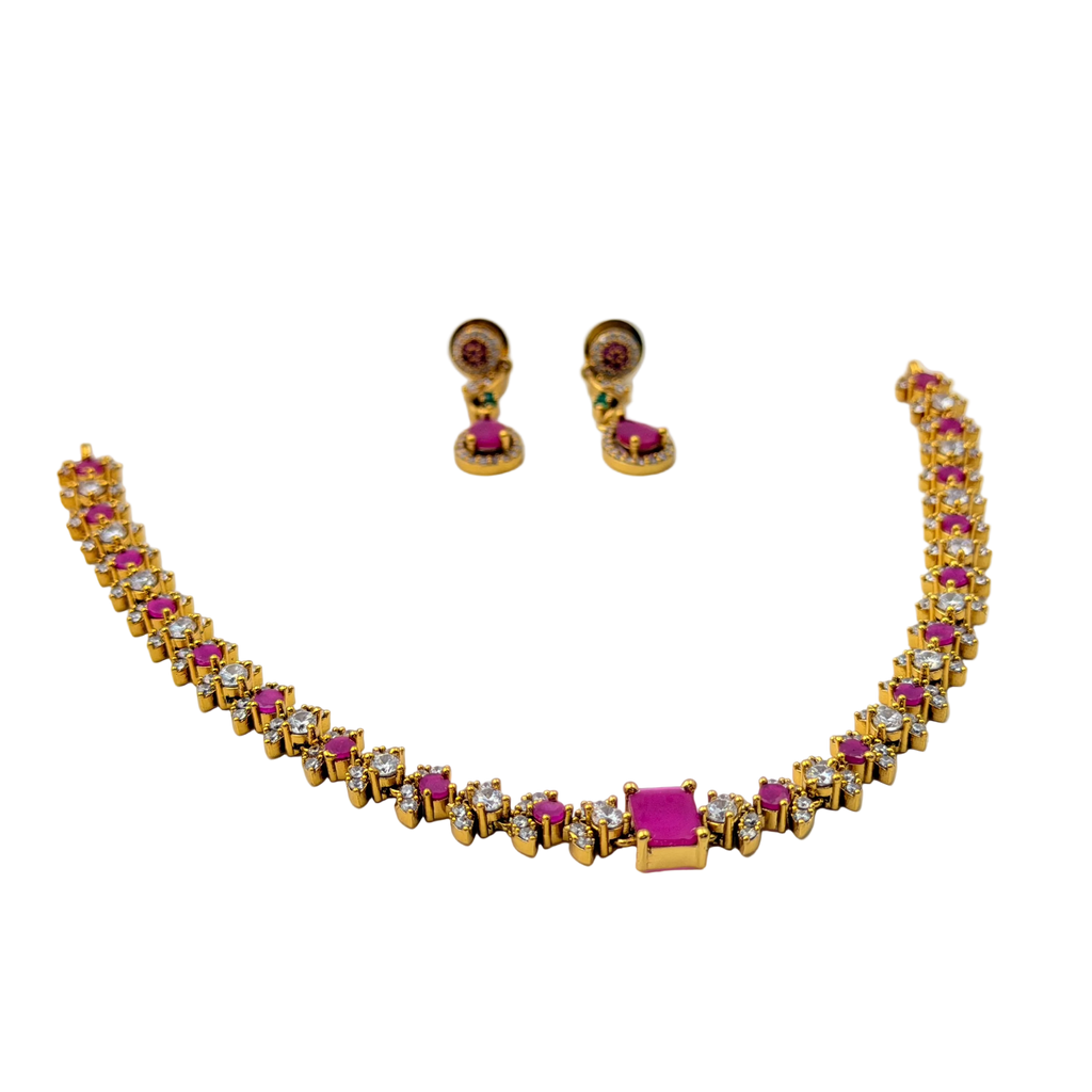Gold necklace with pink and clear stones and matching earrings on a white background