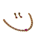 Gold necklace with red and clear gemstones and matching earrings on a white background