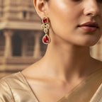 Gold ruby red crystal drop statement earrings with pave halo, shown on model's ear