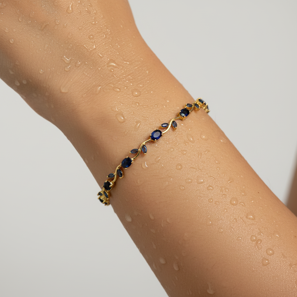 Gold bracelet with blue stones on a person's wrist against a light gray background
