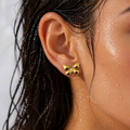Gold butterfly earring worn by a person with wet hair.
