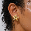 Gold flower-shaped earring worn by a person with wet hair.