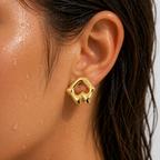 Gold-tone sculptural open-work stud earring with mirror-shine finish, shown worn on ear