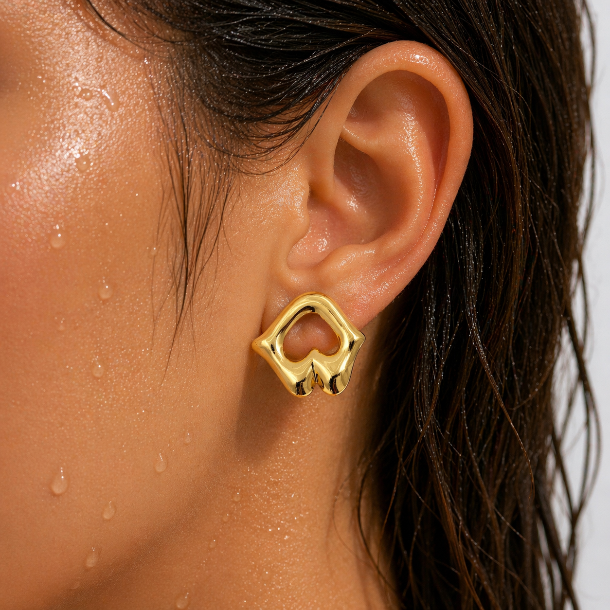 Gold earring worn by a person with a neutral background
