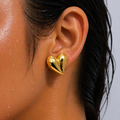 Gold heart-shaped earring worn by a person with wet hair.