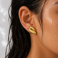 Gold earring worn by a person with a neutral background