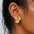 Gold flower earring worn by a person with wet skin