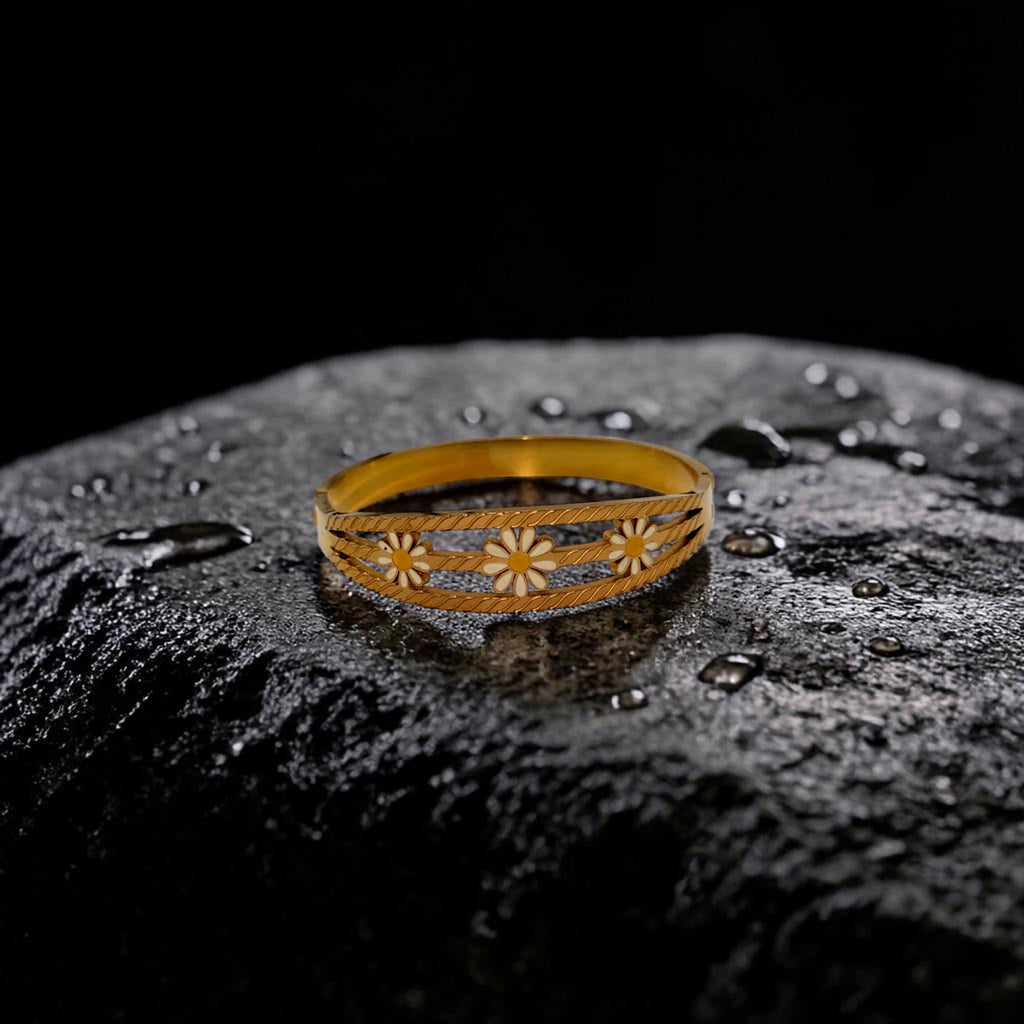 Gold bracelet with floral designs on a textured black surface