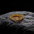 Gold bracelet with floral designs on a textured black surface