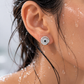Close-up of an ear wearing a silver earring with water droplets on skin and hair.