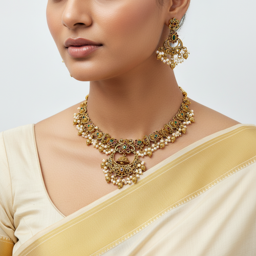 Woman wearing a gold necklace and earrings on a plain background