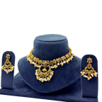 Gold necklace and earrings set on a blue velvet stand with a white background
