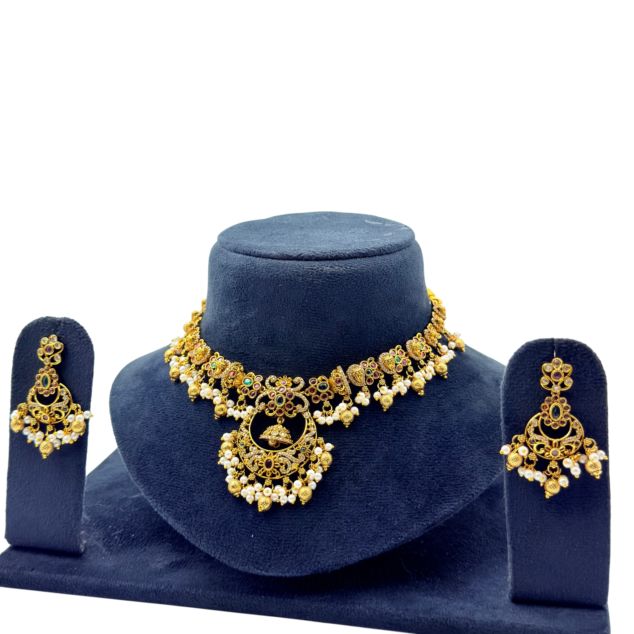 Gold necklace and earrings set on a blue velvet stand with a white background