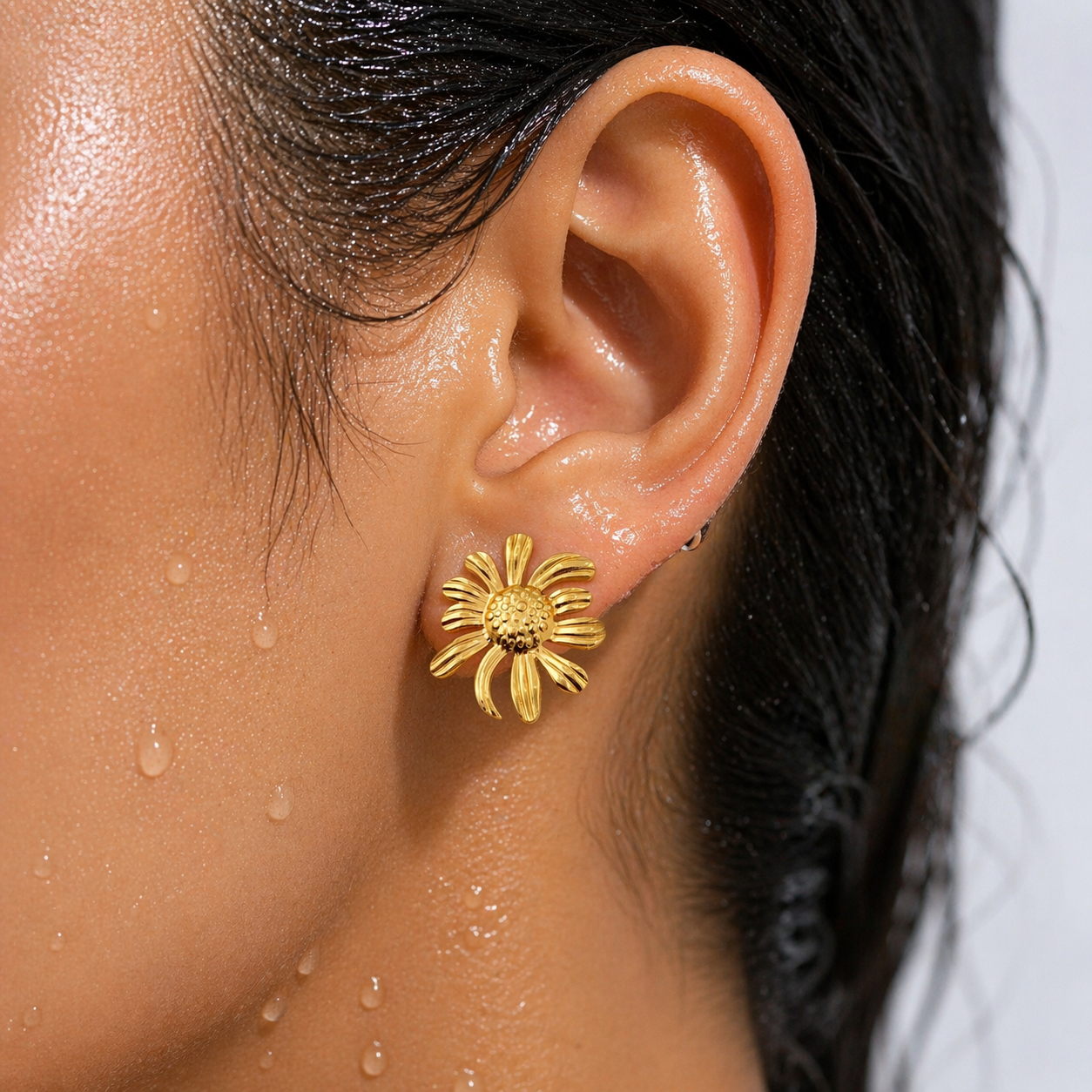 Close-up of a person wearing a gold sunflower earring.