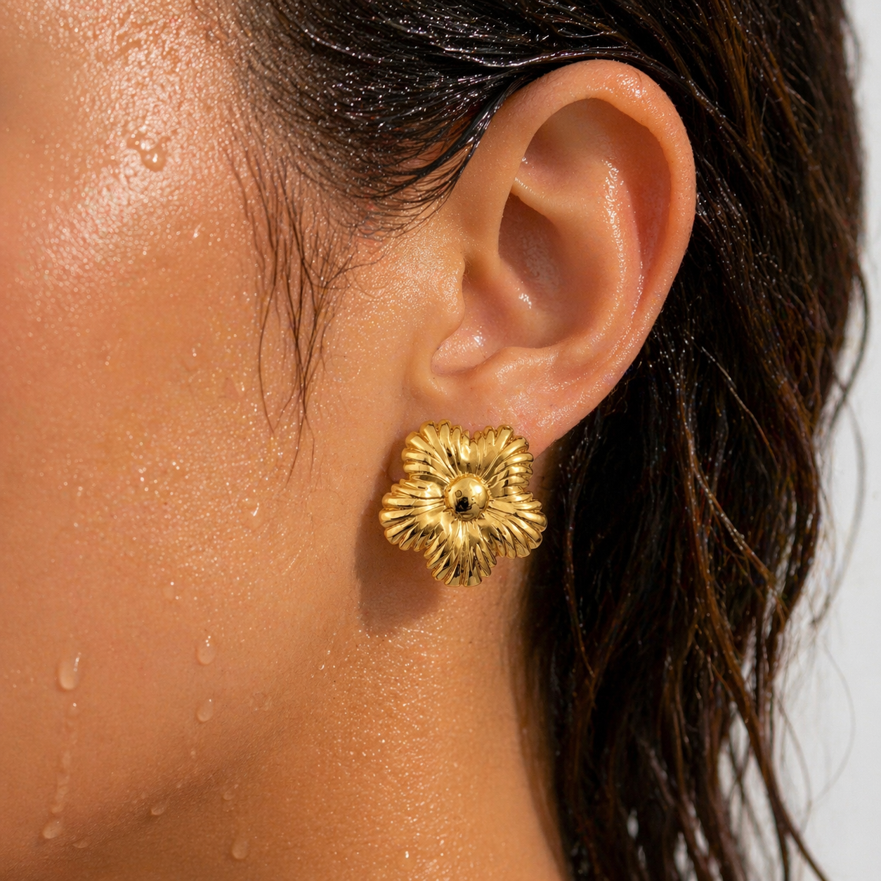 Close-up of a person wearing a gold floral earring.