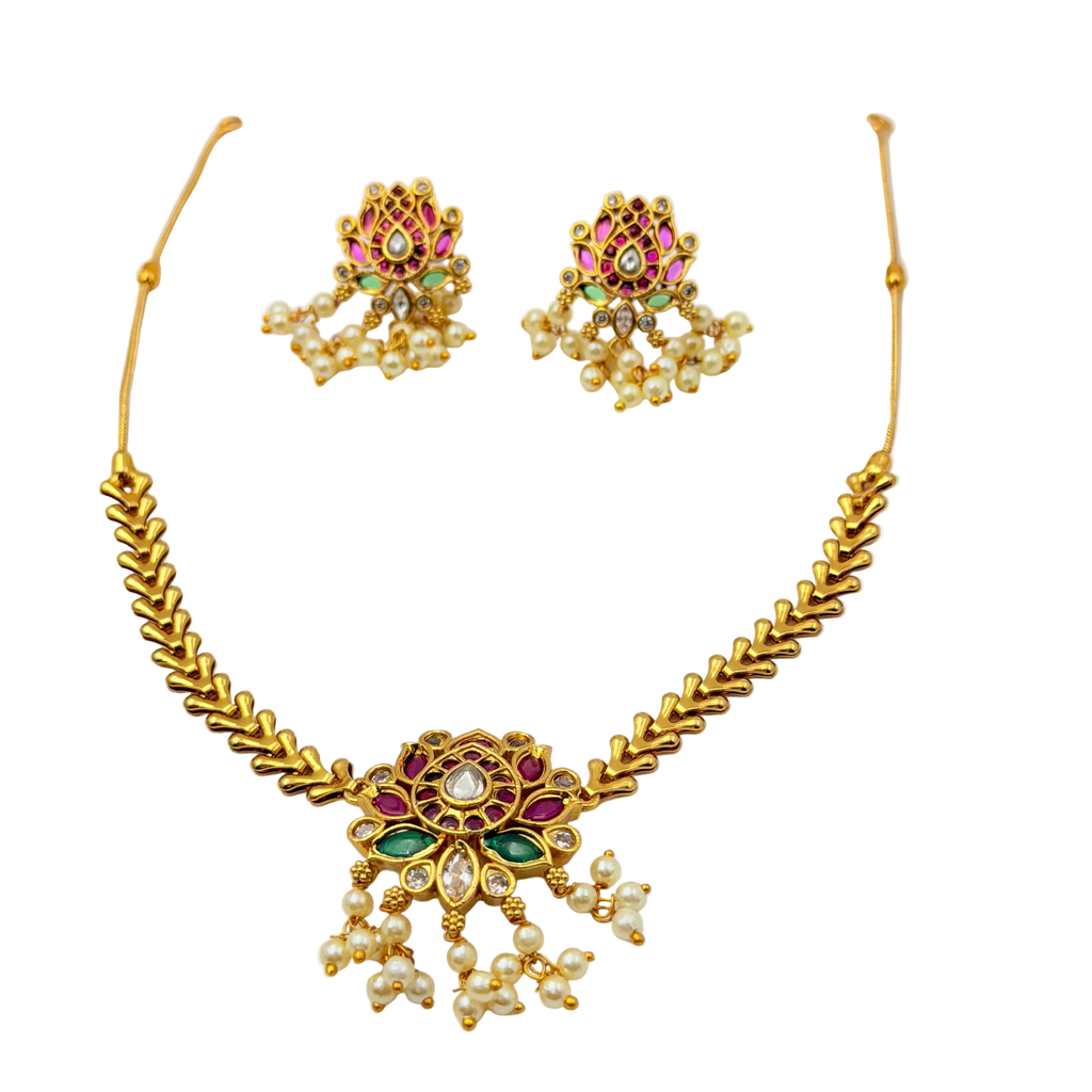 Gold necklace and earrings set with gemstones on a white background