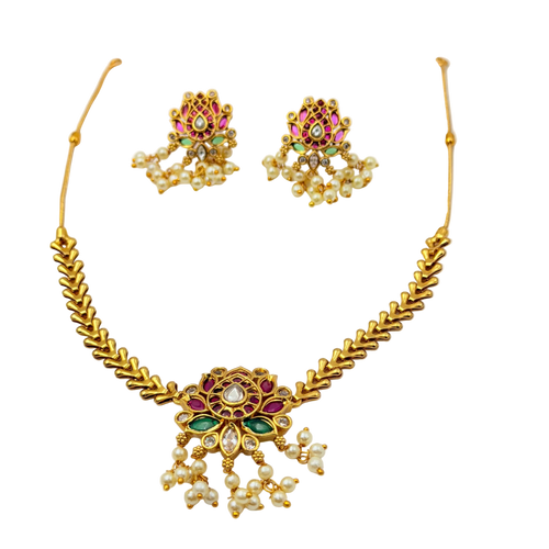 Gold necklace and earrings set with gemstones on a white background