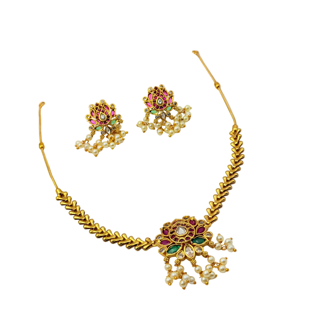 Gold necklace and earrings set with gemstones on a white background