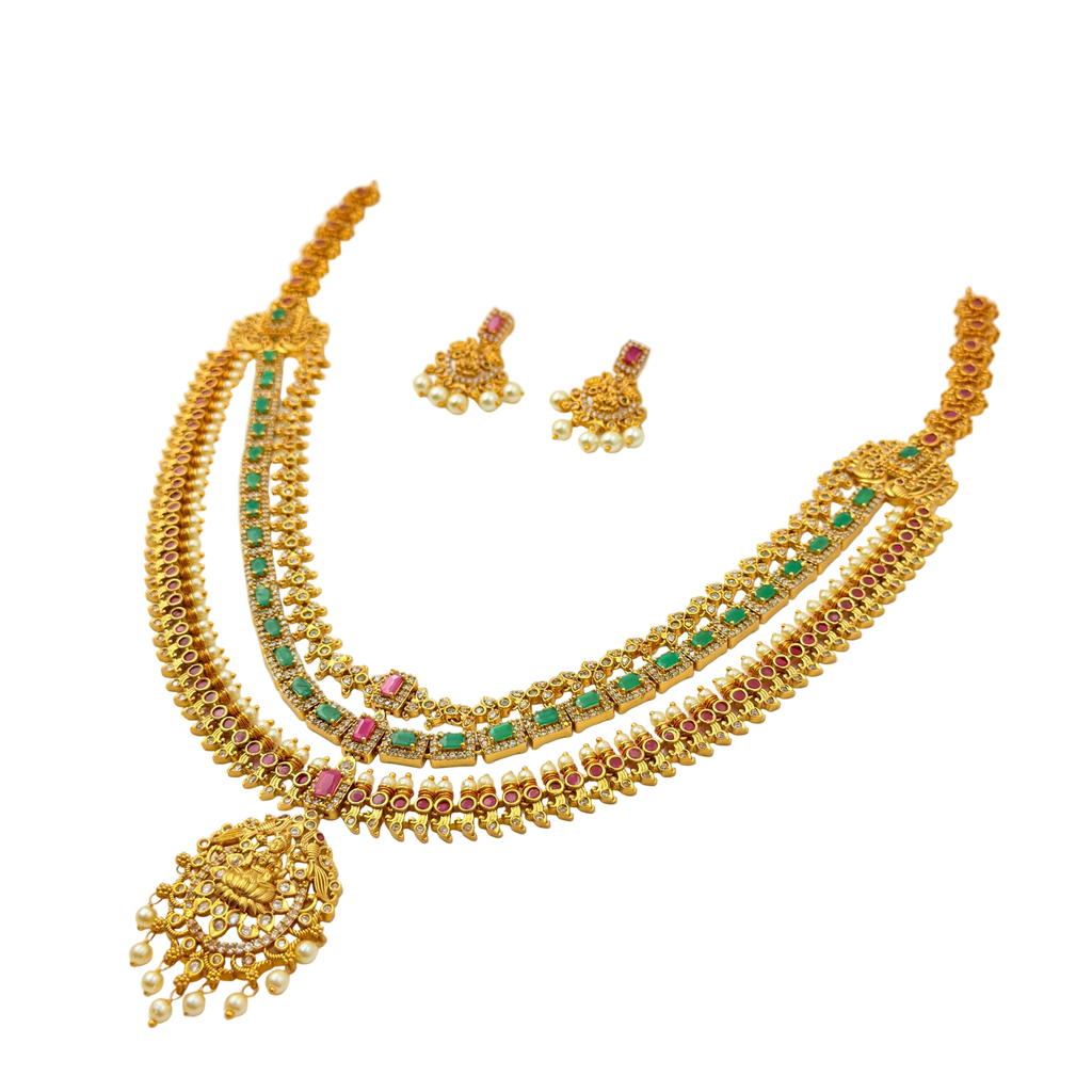 Gold necklace with green and red stones on a white background