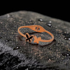 Rose gold bracelet with a butterfly design on a textured black surface