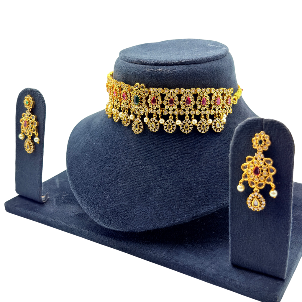 Gold vintage floral choker necklace and drop earrings with ruby and emerald stones, angled display view