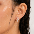 Close-up of an ear wearing a diamond earring with water droplets on skin and hair.