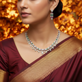 Gold-tone amethyst and emerald crystal necklace set with drop earrings, worn by model in maroon saree