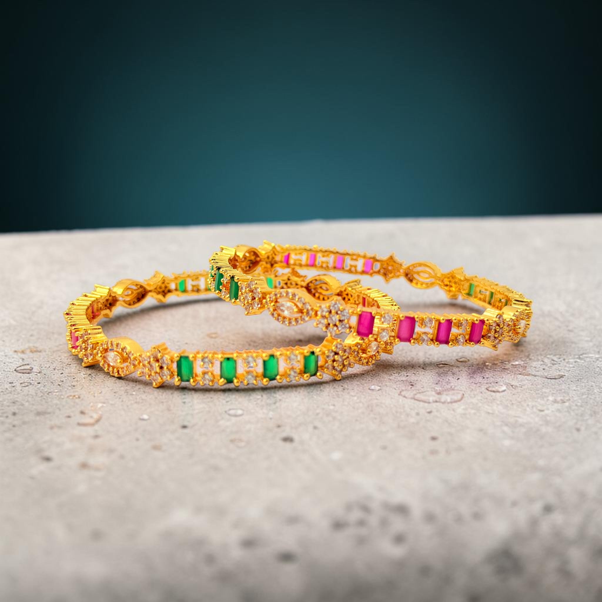 Gold bracelets with colorful stones on a textured surface