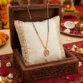Decorative jewelry display with a necklace on a white pillow inside a wooden box, set against a festive background.