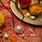 Decorative setting with colored powders, flowers, and a necklace on a red and gold patterned fabric.