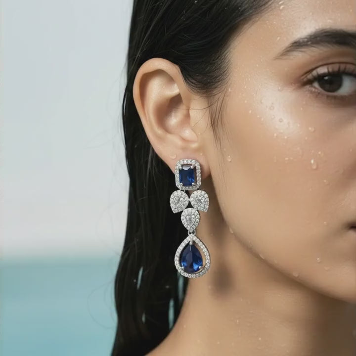 Silver-tone royal blue crystal drop statement earring with floral cluster, close-up on model's ear