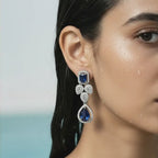 Silver-tone royal blue crystal drop statement earring with floral cluster, close-up on model's ear