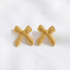 KJ-AI-GALLERY-v1 | Textured Ribbon Bow Earrings — styled flat-lay | Krystal Jewels