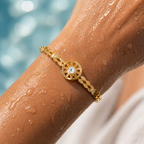 Gold bracelet with a diamond on a wet arm by a pool