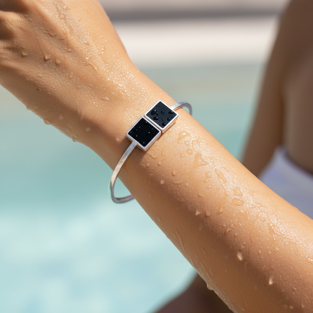 Silver bracelet with black square stones on a person's wrist against a blurred background
