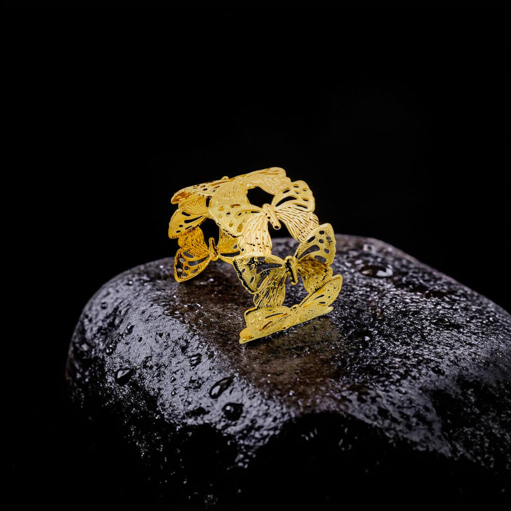 Gold butterfly-shaped bracelet on a dark stone surface with a black background