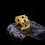 Gold butterfly-shaped bracelet on a dark stone surface with a black background