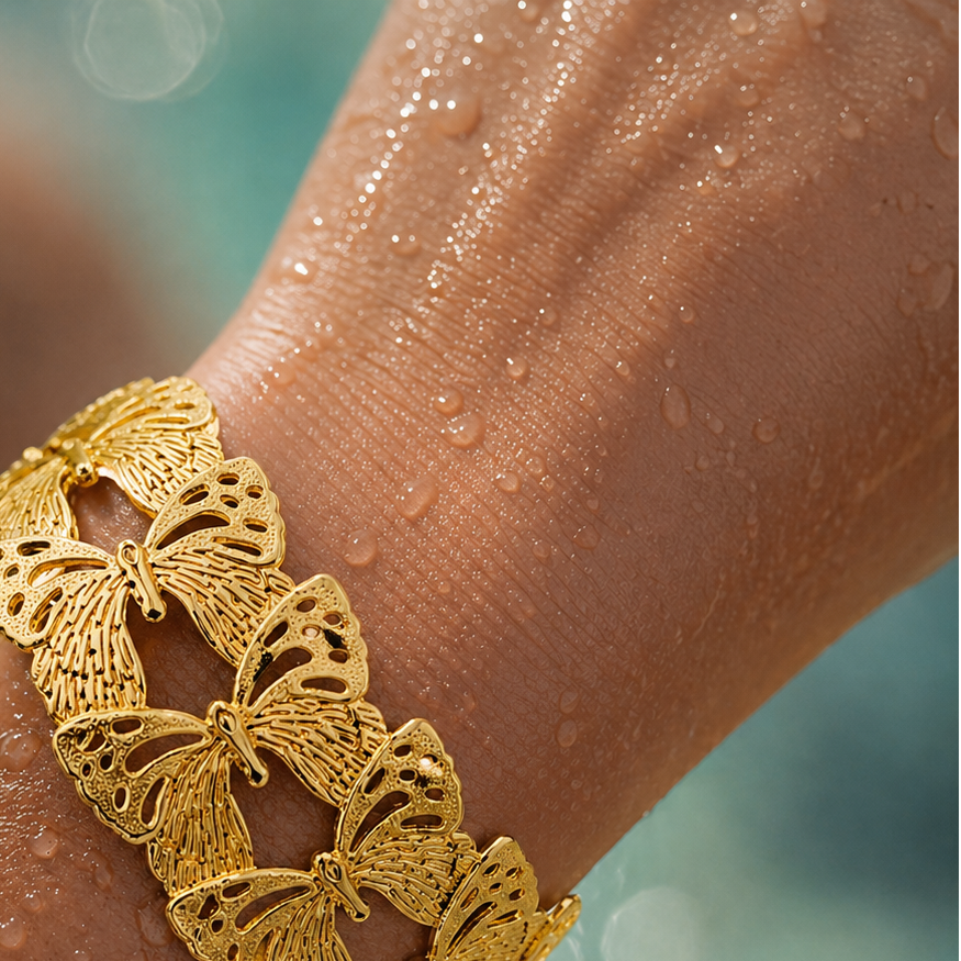 Gold butterfly bracelet on a wet arm with a blurred background
