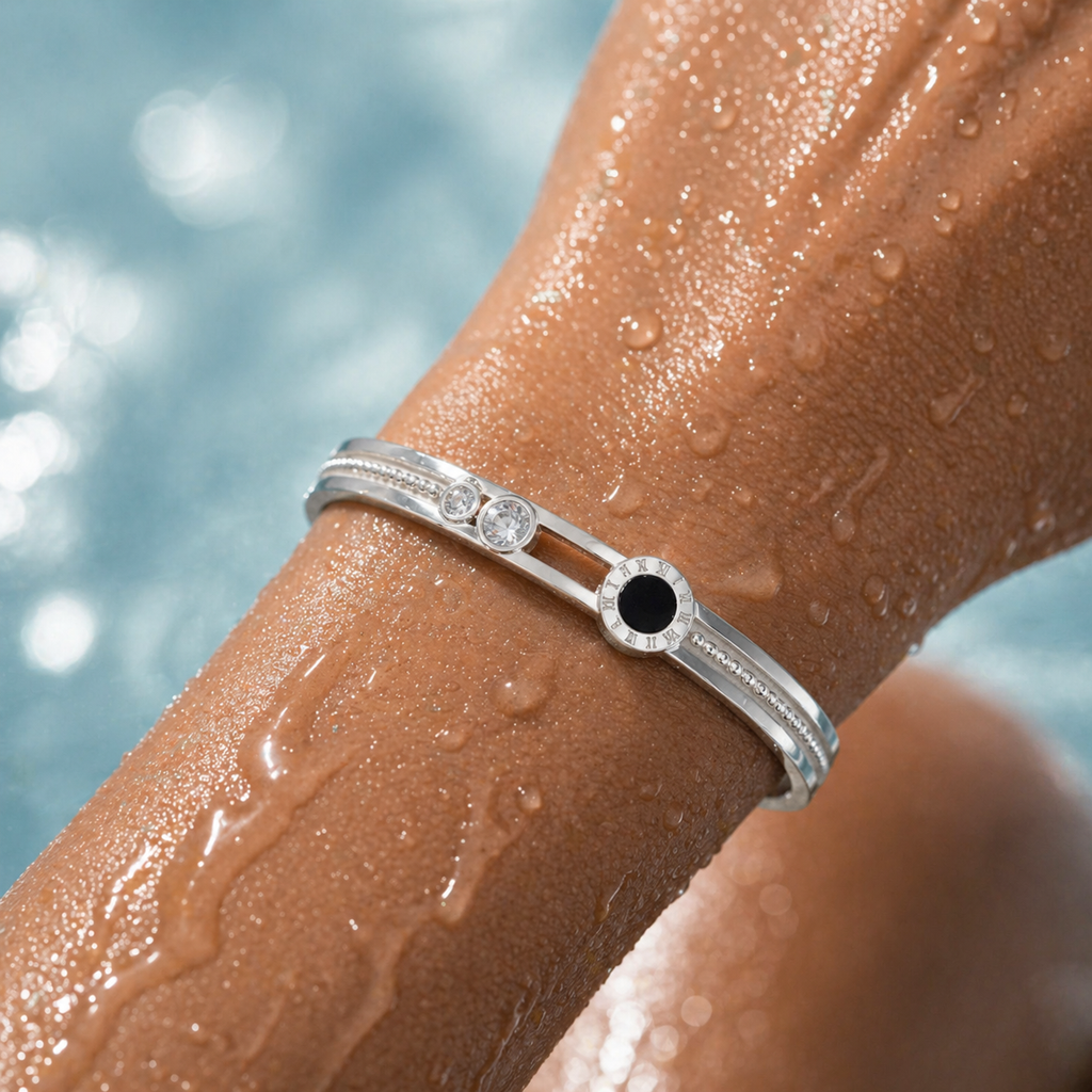 Silver bracelet with a black gemstone on a wet arm against a blurred water background