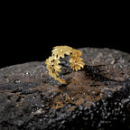 Gold floral ring on a textured dark surface with a black background