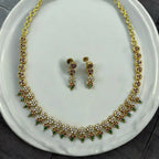 Gold-plated floral necklace and earrings set with crystal, ruby and green accents, worn by model in a gold saree